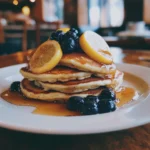 Blaubeer-Zitronen-Pfannkuchen serviert mit Ahornsirup.